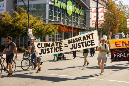 Foto de Vancouver, Canadá - 15 de septiembre de 2023: Activistas con un cartel: Justicia Migrante Justicia Climática caminando por Cambie Street como parte de la Huelga Climática Global en Vancouver - Imagen libre de derechos
