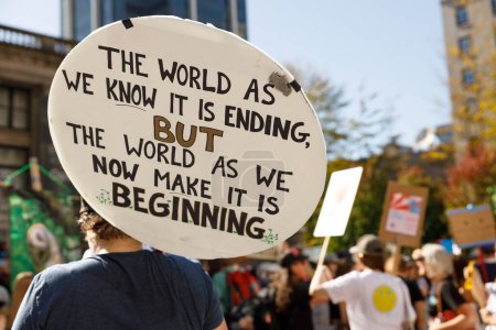 Foto de Vancouver, Canadá - 15 de septiembre de 2023: Activista con una señal: El mundo tal como lo conocemos se está acabando, pero el mundo tal como lo hacemos ahora está comenzando como parte de la Huelga Climática Global en Vancouver - Imagen libre de derechos