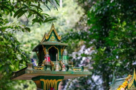 Téléchargez les photos : Koh Samui, Thaïlande - 11 décembre 2023 : À l'entrée de la cascade Namuang sur Koh Samui, se dresse une maison spirituelle thaïlandaise traditionnelle ornée d'offrandes alimentaires, incarnant les coutumes locales et la spiritualité - en image libre de droit