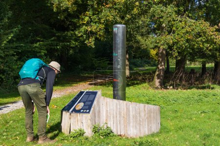 Foto de Borger, The Netherlands - October 16, 2022: Senior man reading information sign beside ground water measurement system in park in Borger Hondsrug in Drenthe The Netherlands - Imagen libre de derechos