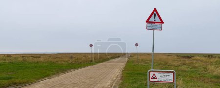 Téléchargez les photos : Mando, Denmark - Novemebr 15, 2022: Stop and warning signs at dirt road to island Mando dangerous while this road floods twice per day during high water tide. - en image libre de droit