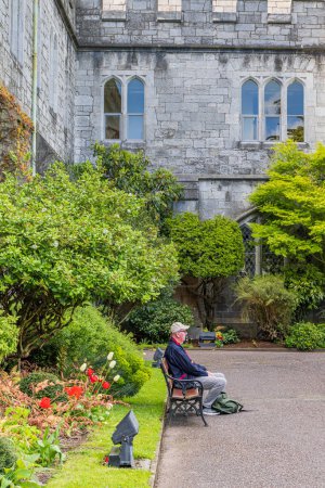 Cork, Ireland - April 17, 2023: Man at bench relaxing at bench in gardens University College of Cork Munster province in Ireland Europe