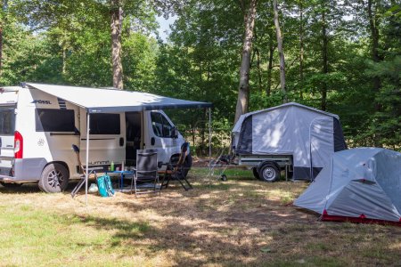 Photo for Exloo, The Netehrlands - July 2, 2023: Campervan, folding trailer and tent at campsite between the trees in Drenthe province in The Netherlands - Royalty Free Image