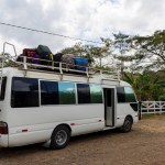 Small white tourist bus with luggage stacked on the rooftop traveling through Nicaragua in Latin america