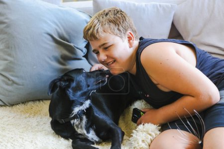 Photo for Teen boy snuggling on couch with pet dog. Man's best friend. Black kelpie cross labrador breed. - Royalty Free Image