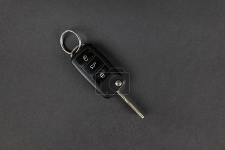 Photo for Modern car keys isolated on black background with copy space for text. Folding key with remote alarm and trunk release. View from above. - Royalty Free Image