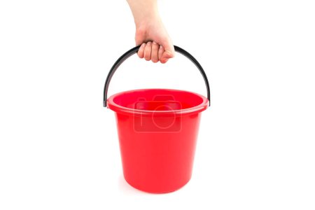 Photo for A human hand holds a red plastic bucket of water on a white background. - Royalty Free Image