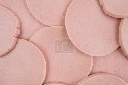 Slices of tasty boiled sausage as background, top view