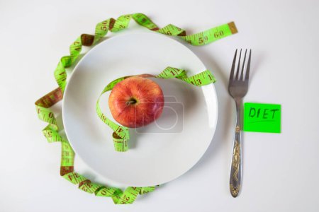 Photo for Red apple and measuring tape on a plate as a symbol of healthy eating. - Royalty Free Image