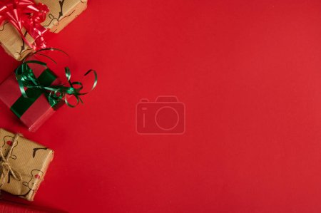 Foto de Bodegón de Navidad con regalos en la esquina de un fondo rojo. Copia el espacio publicitario. Burla, diseño de texto promocional. Día de Boxeo. Preparativos de Navidad y Año Nuevo. Embalaje de regalos. Banner web. Puesta plana - Imagen libre de derechos