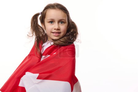 Foto de Retrato de cerca del ciudadano americano, niña envuelta en bandera canadiense, aislada sobre fondo blanco. Día de la Independencia de Canadá. Día del Dominio. 1 de julio. Concepto de emigración y ciudadanía - Imagen libre de derechos