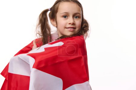 Foto de Ciudadano canadiense, encantadora niña envolviendo la bandera de Canadá, celebra el Día de la Independencia, Día del Dominio, 1 de julio. Derechos humanos y libertades, aislados sobre fondo blanco con espacio para su promoción - Imagen libre de derechos