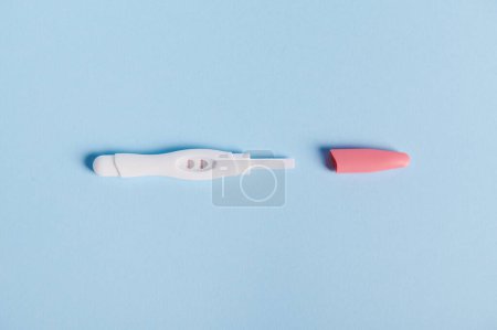 Photo for Isolated shot of positive pregnancy test kit with two strips on blue pastel color background. Motherhood concept. Womens health and fertility concept. Finally pregnant. Health care Medicine. Flat lay - Royalty Free Image