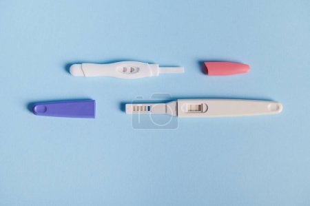 Foto de Top view pruebas de embarazo de inyección de tinta con la reacción bioquímica que tiene lugar entre la orina femenina y la hormona gonadotropina humana coriónica, que aparece en dos barras, sobre fondo azul. Finalmente embarazada - Imagen libre de derechos
