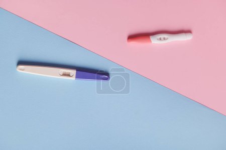 Photo for Rapid diagnosis of pregnancy. Pregnancy tests with two bars on isolated blue and pink color pastel background. Copy space. Womens health, gynecology and medicine concept. Planning maternity concept - Royalty Free Image