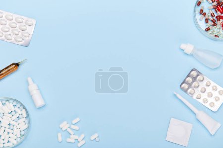 Flat lay. Medical pills, translucent capsules, blisters with dragees, drops and ampoules laid out on blue background, copy space for insert advertising text. Pharmaceutical industry. World Health Day