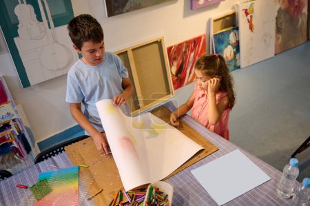 Foto de Vista desde arriba de dos niños lindos caucásicos dibujando en taller de arte creativo. Aprendiendo. Pintura. Educación y entretenimiento para niños. Desarrollo de habilidades artísticas en el estudio de arte creativo o galería de arte - Imagen libre de derechos