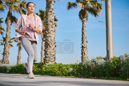 Photo for Full length portrait of young woman runner jogging on the treadmill, enjoying a marathon of Breast Cancer Awareness campaign. Pink October. Sport, empathy, tolerance, support. Social issues. Ad space - Royalty Free Image