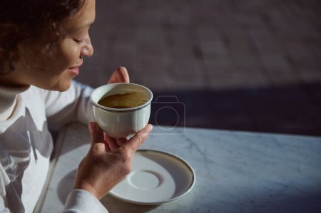 Detalles de una elegante taza de porcelana de cerámica blanca con los restos de una bebida de café en una feliz mujer sonriente sentada en una cafetería y contando fortunas en terrenos de café. Gente. Ocio. Estilo de vida