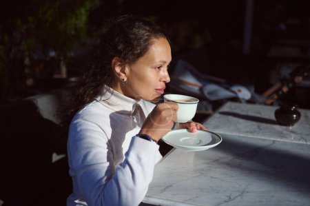 Portrait of a confident serious African American young business woman enjoying her hot drink in the outdoor terrace of a cafe