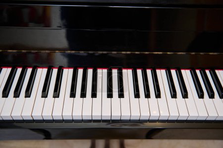 Primer plano de un teclado de piano vintage de madera negra, con teclas en blanco y negro. Naturaleza muerta. Instrumento clásico de acordes musicales