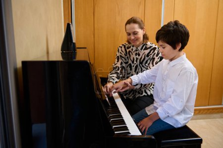 Authentique enseignante de musique expliquant une leçon de piano à son élève lors d'une leçon de musique individuelle à la maison. Éducation musicale et développement artistique pour les jeunes et les enfants. Loisirs et loisirs