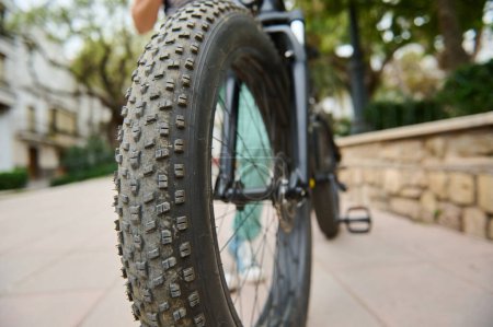Selective focus on tubeless tire of an electric motor bike, mountain bike. Shallow tread of a bicycle tubeless tire. Cropped view of electric bike bicycle wheel with spokes. Copy ad space