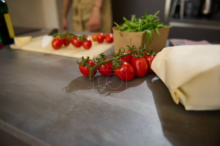 Foto de Un manojo de cereza de tomate orgánico maduro dulce en el mostrador de la cocina. - Imagen libre de derechos