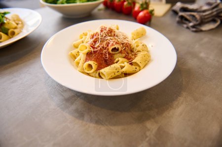 Téléchargez les photos : Pâtes italiennes penne avec sauce tomate et basilic sur plaque blanche sur fond de marbre. Boucherie de nourriture - en image libre de droit