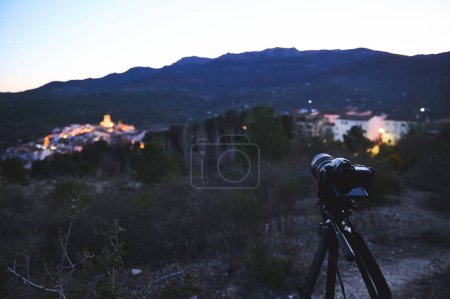 Photo for A digital camera placed on tripod, capturing the medieval village of Quesada in mountains Sierra de Cazorla at sunrise. Blurred mountains on the background. Travel photography. World photography Day - Royalty Free Image