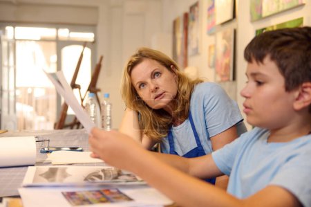 Kinder haben Kunstunterricht, Zeichnen, Malen mit dem Lehrer in der Werkstatt. Lehrer leitet Schüler bei der Entwicklung künstlerischer Fähigkeiten.