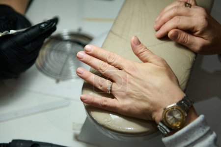 La imagen del primer plano de las manos durante la manicura en el salón de belleza. Técnico profesional en uñas que utiliza herramientas para cuidar las uñas del cliente.