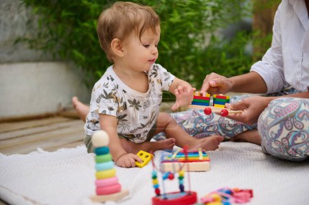 A cute toddler enjoys interactive play with colorful toys outdoors. Developing fine motor skills and creativity in a serene environment.