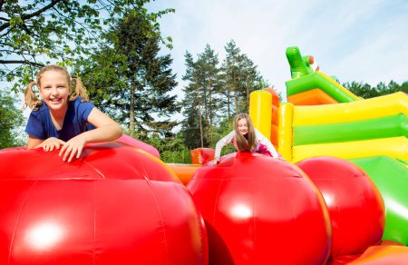 Foto de Feliz niñas teniendo un montón de diversión mientras salta de la pelota a la pelota en un castillo inflado. - Imagen libre de derechos