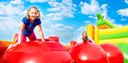 Foto de Feliz niñas teniendo un montón de diversión mientras salta de la pelota a la pelota en un castillo inflado. - Imagen libre de derechos