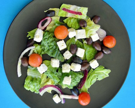 Photo for A Greek salad on a black plate against a colorful background - Royalty Free Image