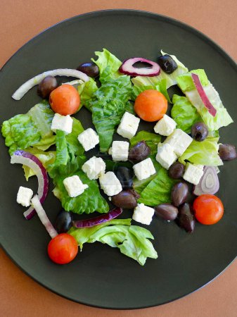Photo for A Greek salad on a black plate against a colorful background - Royalty Free Image