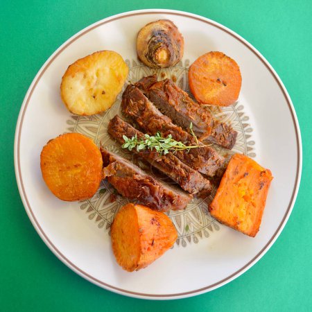 A baked dinner featuring slices of lamb with vegetables on a plate