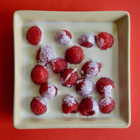 raspberries and thickened cream in a dish.