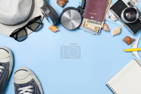 Photo for Traveler accessories, vintage camera, dollar banknote in passport and black sneaker on blue  background for summer holiday and vacation concept. - Royalty Free Image