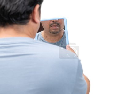 Foto de Hombre barbudo mirando en el espejo para las etiquetas de la piel o acrocordón en su cuello aislado sobre fondo blanco. Concepto de salud - Imagen libre de derechos