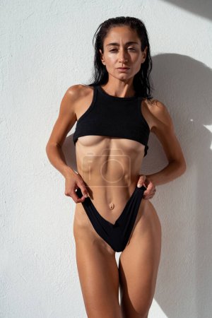 Eine schöne, sexy Brünette mit einem sportlichen Körper posiert in schwarz