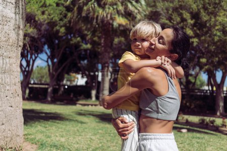 Junge Mutter umarmt ihren vierjährigen Sohn im Park