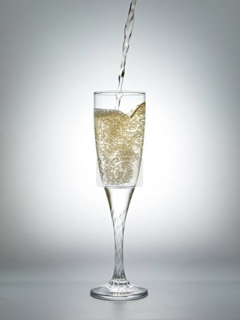 Foto de Verter champán en una copa sobre un fondo gris. Profundidad superficial del campo - Imagen libre de derechos