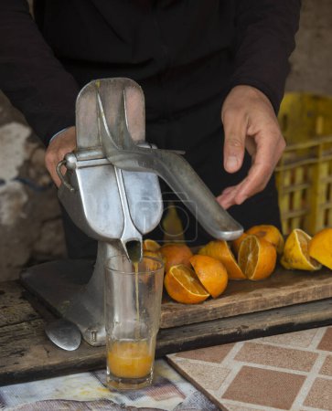 Photo for A hand of men is squeezing orange fruit using manual hand press juice - Royalty Free Image