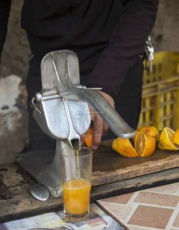 Photo for A hand of men is squeezing orange fruit using manual hand press juice - Royalty Free Image