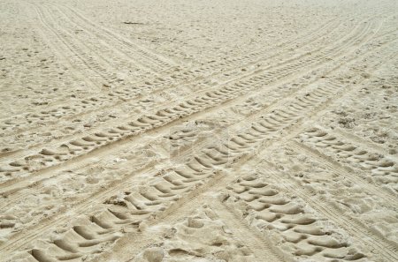 Téléchargez les photos : Traces croisées de pneus de véhicule dans le sable mouillé dans le ciel nuageux da - en image libre de droit