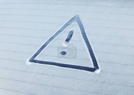Foto de Un triángulo de advertencia dibujado en el hielo en una ventana trasera congelada de un coche. - Imagen libre de derechos