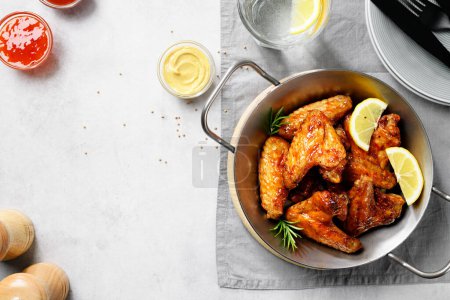 Air fryer chicken wings glazed with hot chilli sauce and served with different sauces.  gray background . top view
