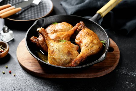 Téléchargez les photos : Jambes de canard fraîchement rôties confit dans une casserole, fond noir - en image libre de droit